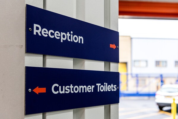 An image of indoor wayfinding signage for Reception and Bathrooms.